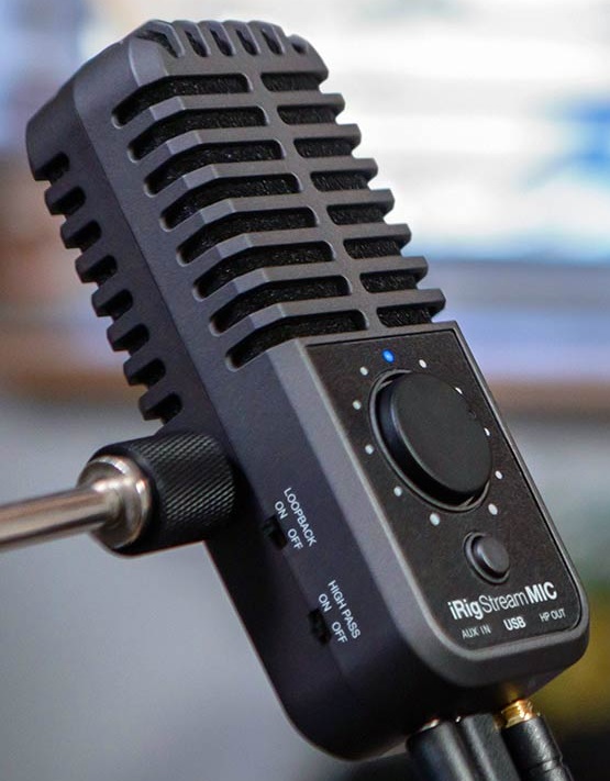 Semi-front view of the iRig Stream Mic USB with blurred room background.
