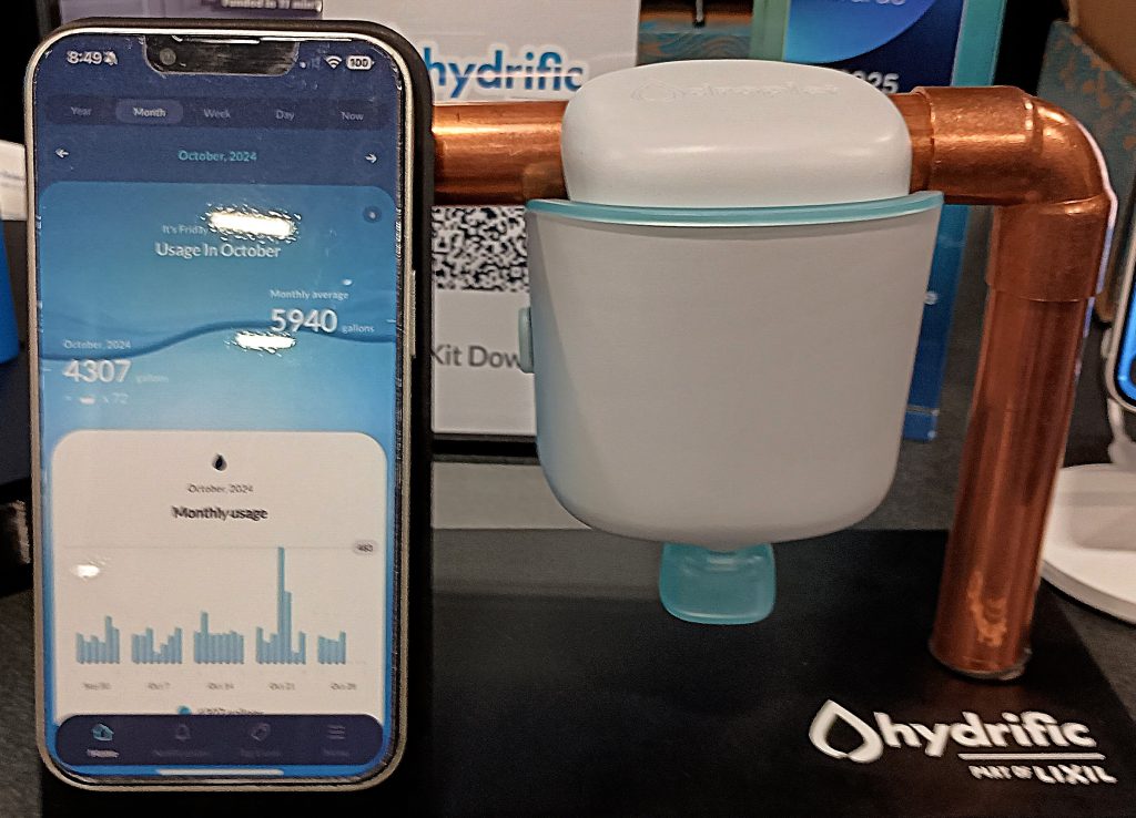 Droplet water sensor clamped to copper pipe and mobile app displayed on phone.