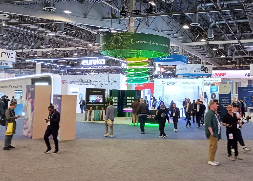 Interior of Venetian Expo Hall A with attendees walking around several large company exhibit booths.