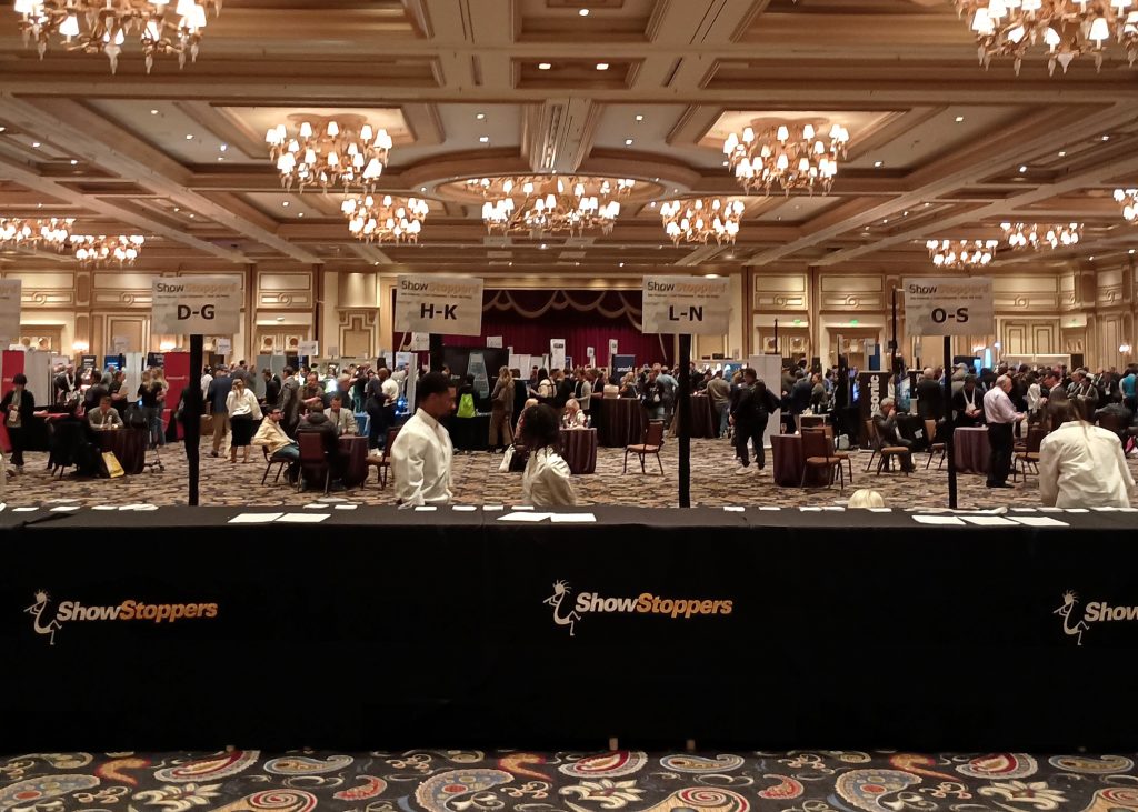 Registration counter at the entrance to the ShowStoppers event, with company exhibit booths in the ballroom behind.