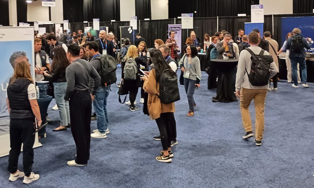 Attendees gathering around tables and booths inside CES Unveiled.