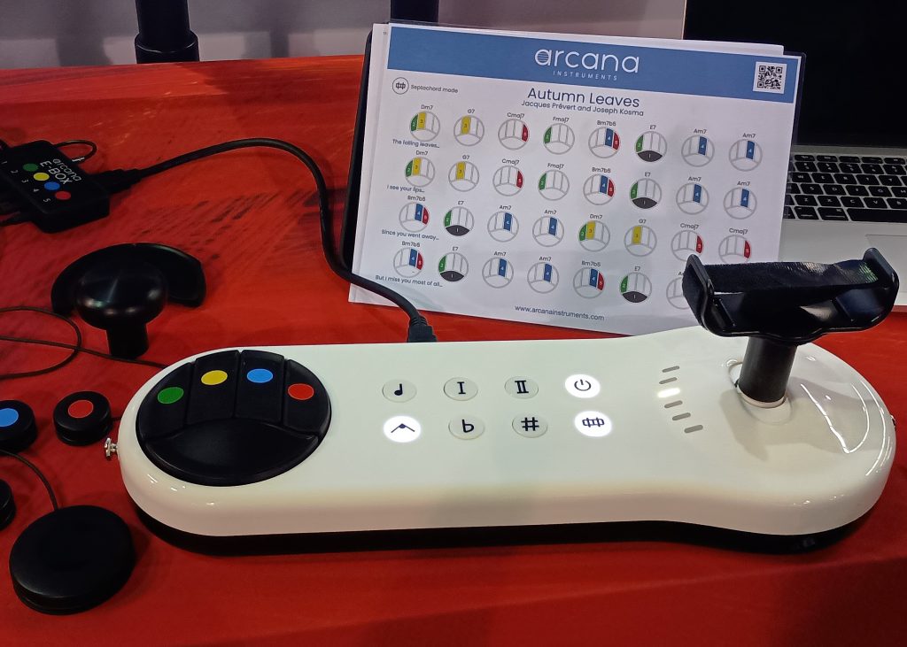 Aracana Strum accessibility instrument with peripheral buttons to the left and color coded note sheet behind.