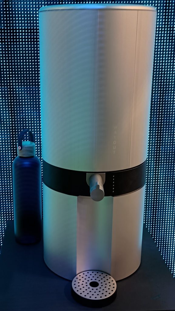 Wayout Tap cylindrical water dispenser in white with a blue and black LED wall behind.